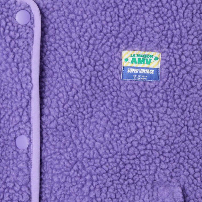 Close-up of a purple textured fabric with a brand label on a white background